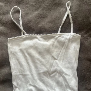Vit ribbad linnetopp från H&M  - Säljer en vit ribbad linnetopp från H&M Divided. Toppen har smala axelband med söt spetskant upptill och är tillverkad i mjuk bomullsmix. Perfekt för sommardagar eller att styla lager på lager. Den är en typ av coquette linne skulle jag säga. Det är min kompis gamla linne, så vet inte hur mycket den är använd. Den ser helt oanvänd ut. Säljer för 50kr med frakt av 20-40 kr är osäker på priset. Köp inte på ”KÖP NU” , betalningen genomförs i chatten med Swish. 