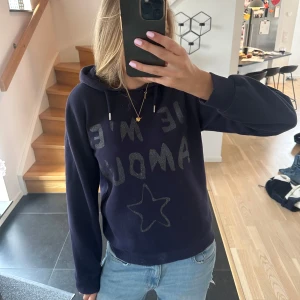 Mörkblå hoodie med glittertext - Säljer en mörkblå hoodie från Gina young . Framsidan har glittrig text och en stjärna i silver. Perfekt för dig som gillar en chill och snygg stil! Storleken är 146/152 men den passar mig som normalt sätt har XS/S