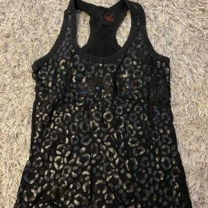 Svart leopardmönstrat linne - Svart linne med glansigt leopardmönster och paljetter.