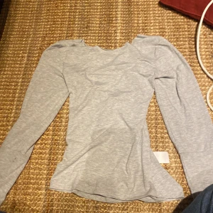 Grå långärmad topp Chiara Forthi XS - En grå långärmad tröja som sitter tajt vid midjan och är öppen i ryggen, har använt 2-3 gånger, jätte skön tröja i storlek xs