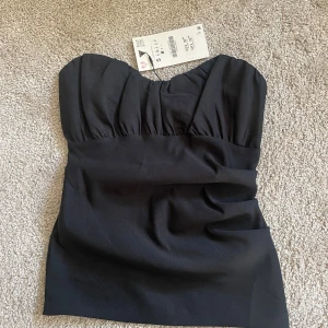 Svart bandeau tubtopp från Zara - Säljer min svarta bandeau tubtopp från Zara då den är för liten, storlek S. Aldrig använd endast testad, prislapp kvar  ☺️