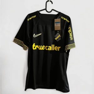 AIK svart matchtröja Nike 2024 - AIK:s officiella svarta matchtröja från 2024 med gula detaljer och tryck från Truecaller, SVEA och Stadium. Klassisk AIK-logga på bröstet och unika mönster på ärmsluten. Tillverkad i lätt och ventilerande funktionsmaterial. Perfekt för dig som vill visa ditt AIK-stöd.
