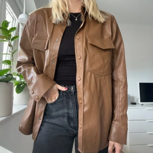 Brun skinn overshirt från Carin Wester - Snygg brun overshirt i skinnimitation från Carin Wester. Jackan är storlek XXL men passar väldigt bra som en oversized shirt på mig som har S/M. Använd 2-3 gånger 