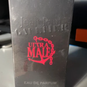 Jean Paul Gaultier Ultra Male parfym - Jean Paul Gaultier Ultra Male Eau de Parfum 125ML  i svart förpackning med röd text och ankare. En maskulin doft med intensiv karaktär, perfekt för dig som gillar starka och unika parfymer. Snygg design som sticker ut i badrumshyllan.