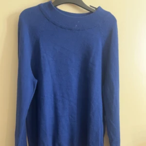 Blå stickad långärmad tröja - En enkel och stilren blå stickad tröja med lång ärm och rund halsringning. Perfekt att slänga på sig när det är lite kyligare ute. Tröjan har en klassisk passform och är lätt att matcha med jeans eller kjol.