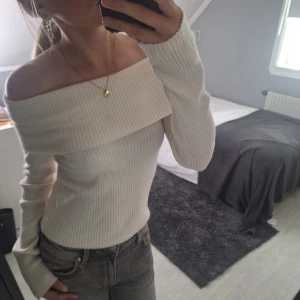 Offshoulder ribbad topp från H&M - Superfin offshoulder topp från H&M i ribbad, mjuk och stretchig kvalitet. Toppen är ljusbeige, har långa ärmar och sitter snyggt figurnära. Perfekt för dig som gillar en stilren och trendig look.