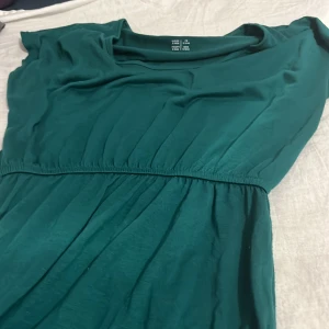Grön klänning från Esmara S - Mörkgrön klänning från Esmara i storlek S. Klänningen har korta ärmar, markerad midja med resår och är tillverkad i mjukt, lätt material. Enkel och stilren design som passar perfekt för dig som gillar en avslappnad men snygg look.