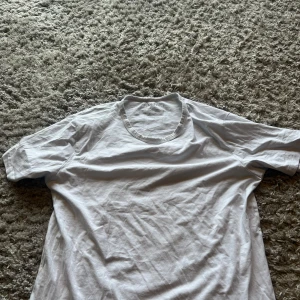 Vit t-shirt från Jack & Jones - En klassisk vit t-shirt från Jack & Jones med rund hals och korta ärmar. T-shirten är gjord i mjuk bomull och har en enkel, clean look som funkar till allt. Perfekt för dig som gillar basic och stilrent. Storleken kan vara svår så skriv om ni har frågor 