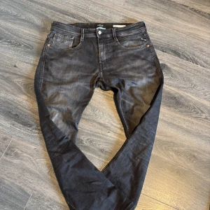 Svarta Replay jeans i slim fit - Säljer ett par svarta Replay jeans med snygg tvättad look. Jeansen har klassisk femficksdesign, raka ben och diskreta sömmar på bakfickorna. Passformen är anbass (slim) och materialet är mjukt jeans i bomull. Perfekta för dig som gillar stilrena och bekväma jeans. Jeansen är i storlek 34-32 men sitter mer som 32/32. Köpta för 1500 och u otroligt bra pris