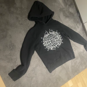 Svart hoodie från Jack & Jones - !!vintage!! Svart hoodie från Jack & Jones Vintage Denim med stor, sprucken tryckt glob och text på bröstet. Klassisk huva och muddar vid ärmslut. Perfekt för dig som gillar streetstyle och vill ha en tröja med coolt tryck. Skriv vid minsta fundering 💫⭐️🤩