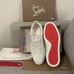 Vita Louboutins - Exklusiva vita skor från Christian Louboutin med ikonisk röd sula och guldfärgad logga på insidan. Skorna är i skinn och har klassisk snörning. Perfekta för dig som vill sticka ut med stilrena och lyxiga detaljer.