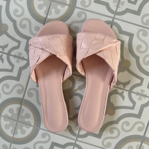 Flätade ljusrosa sandaler i skinn bottega - Snygga ljusrosa sandaler med flätad rem över foten och platt sula. Skorna har öppen tå och är tillverkade i skinn. Perfekta för varma dagar och ger en trendig touch till din outfit.