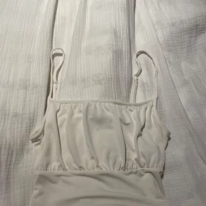 Vit linnetopp  - Säljer en stilren vit linnetopp från Divided H&M i storlek XS. Toppen har smala axelband och lätt rynkade detaljer framtill som ger en snygg form. Perfekt för varma dagar och enkel att matcha med jeans eller kjol 😍