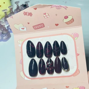 Svarta och vinröda lösnaglar med mönster - Snygga lösnaglar i mandelform med svart och vinröd marmoreffekt, en nagel har 3D-blommönster och en har metallickant i guld. Glansig finish och cool design, perfekt för dig som vill sticka ut med dina naglar.