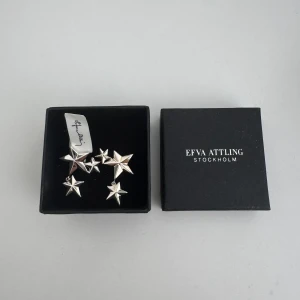 Efva Attling stjärnörhängen i silver ”catch a falling star” - Coola örhängen från Efva Attling i äkta silver med flera stjärnformade detaljer. Snygg design där stjärnorna hänger i olika nivåer. Aldrig använda. NYPRIS 1890:-