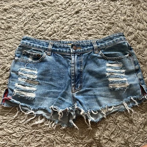 Lågmidjade jeansshorts - Blå lågmidjade vintage jeansshorts med slitningar. Storlek saknas men passar xs-s! Säljer då de är för små. Shortsen är i bra skick!🥰