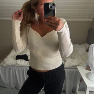 Ribbad ljusbeige v-ringad tröja - Säljer en ribbad ljusbeige långärmad tröja med v-ringad hals. Tröjan har en slim passform och är tillverkad i ett stretchigt, mjukt material som sitter snyggt på kroppen. Perfekt att styla med både jeans och kjol.