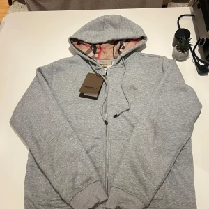 Burberry zip up hoodie - Burberry Zip-Up Hoodie – Strl L ✅ Äkta vara – tag kvar, men kvitto saknas 🧼 Helt oanvänd – inga märken, fläckar eller skador 📦 Originalpåse saknas, men skickas väl förpackad. 👕 Material: 100 % bomull (mjuk och tung kvalitet) 📏 Mått (ungefärliga, plagg lagt platt): – Axel till axel: ca 52 cm – Bröstvidd: ca 58 cm – Längd: ca 70 cm – Ärmlängd: ca 64 cm  ⚠️ Säljes p.g.a. fel storlek 📍 Möts upp Göteborg  i  eller skickas spårbart PRIS KAN DISKUTERAS!!! Ställ frågor om ni har nån 
