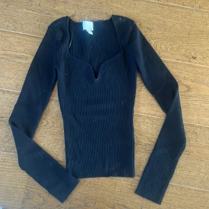 Svart ribbad långärmad topp H&M XS - Svart ribbad långärmad topp från H&M i storlek XS. Toppen har en snygg v-ringning med liten cutout och sitter tight mot kroppen.