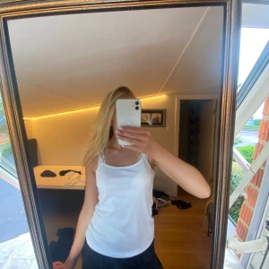 Vit enkel linnetopp med smala band - Säljer en vit linnetopp med smala axelband och rak passform. Toppen är stilren och passar perfekt till sommaren. Materialet känns mjukt och lätt, perfekt för varma dagar.