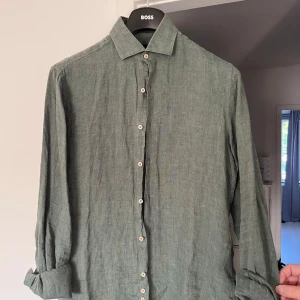 Grön linneskjorta från Park Lane - Snygg grön skjorta i 100% linne från Park Lane. Skjortan har klassisk krage, långa ärmar och vita knappar framtill. Perfekt för dig som gillar en avslappnad men stilren look. Passar lika bra till jeans som till chinos.