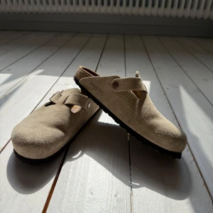 Birkenstock Boston Taupe  - Boston Birkenstock i färgen Taupe med klassisk design och justerbart spänne. Helt oanvända, skick 10/10. 