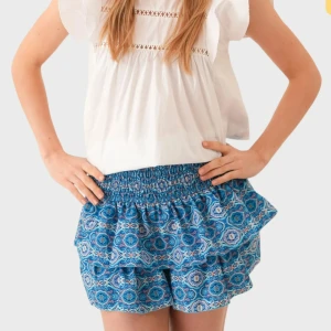 Blå mönstrad volangkjol - Supersöt kort kjol i blått med ett detaljerat mönster och volanger. Kjolen har bred resår i midjan för skön passform och är perfekt för varma dagar. Den har även inbyggda shorts, säljer då jag inte får användning av den💗