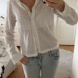 Vit spetsmönstrad skjorta med knappar - Superfin vit skjorta i spetsmönster med blommiga broderier och knappar framtill. Jättesnygg på sommaren!! Aldrig Andvänd 💓