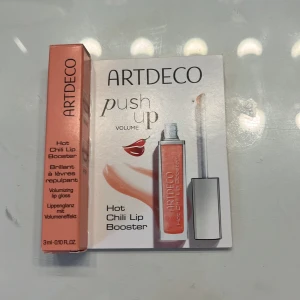 ARTDECO Hot Chili Lip Booster - ARTDECO Hot Chili Lip Booster är ett volymgivande läppglans i en peachig, skimrande nyans. Kommer i en smidig tub med svart lock och applikator. Ger en plumping-effekt och en glansig finish med en hint av chili för extra fylliga läppar.