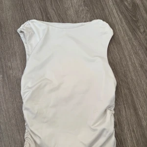 Vit ärmlös kortklänning - Snygg vit kortklänning med ärmlös design och lätt rynkade sidor. Enkel och stilren modell som passar perfekt till varma dagar. Mjuk och bekväm känsla, lätt att matcha med accessoarer.