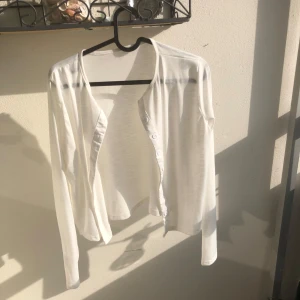 Vit tunn kofta med knappar - Vit, tunn och lätt kofta med långa ärmar och knappar framtill. 