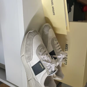 Vita sneakers från Axel Arigato - Snygga vita sneakers från Axel Arigato med grå mockadetaljer , fint skick nypris 1800