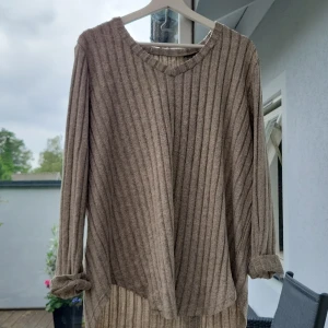 Ribbad beige långärmad tröja - Mysig ribbad tröja i beige med lång ärm och v-ringad hals. Tröjan har en relaxed fit och är perfekt för lager-på-lager. Materialet känns mjukt och passar bra till både jeans och kjol.