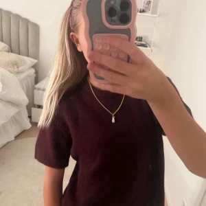 Vinröd stickad kortärmad tröja - Mysig vinröd stickad tröja med korta ärmar och rund hals. Perfekt för lager-på-lager och funkar lika bra till jeans som kjol. Enkel och stilren design utan synliga detaljer eller mönster.