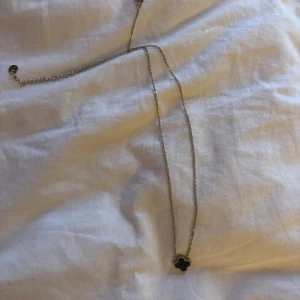 Halsband - Superfint halsband med den ikoniska fyrklöver-hänget i svart och guld. Kedjan är tunn och elegant, och hänget har en pärlad kant som ger extra lyxig känsla. Perfekt för dig som gillar klassiska smycken med en twist.