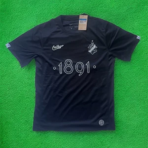 Svart AIK x Nike fotbollströja 1891 - AIK x Nike svart fotbollströja med trycket '1891' på bröstet, AIK:s klubbmärke och Nike-logga i vitt. Tillverkad i lätt och ventilerande Dri-FIT-material, perfekt för träning eller match. Klassisk rund hals och korta ärmar. Snygg detalj med 'SMOKINGLIRARE' i nacken.