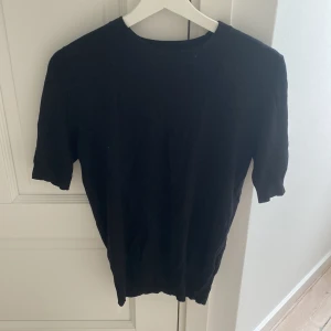 Svart stickad tröja från Zara - Enkel svart stickad tröja från Zara i storlek S. Tröjan har rund halsringning och korta ärmar med ribbade muddar. Perfekt för dig som gillar en clean och stilren look. Passar till allt och är superenkel att matcha med andra plagg.