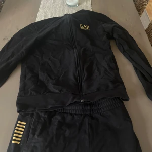 Svart EA7 Dress  med guldtryck - Snygg Emporia armani dress med en zip tröja och byxor. Knappt använda. Ny pris 1999kr 