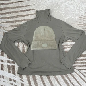 Klädpaket - Grön top med polokrage + mössa  - Snygg och bekväm långärmad topp i mjukt och stretchigt material från Lindex. Färg: olivgrön/grågrön. Perfekt till både vardag och lager på lager under höst och vinter. Storlek: M.  Lindex 94% lyocell, 6% elastan ✅Skick: Mycket gott begagnat skick, inga fläckar eller hål.  Stilren och varm mössa i en fin grön färg från Lager 157. Unisex. Perfekt till höst och vinter! Storlek: One size. 🧵Material: 100% akryl. Mjukt och stretchigt material. ✅Skick: I mycket fint skick – knappt använd 