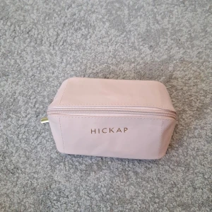 Rosa necessär från Hickap - Säljer en söt, ljusrosa necessär från Hickap med guldig dragkedja och vinrött innerfoder. Praktisk rektangulär form med extra innerficka för småsaker. Perfekt för smink eller andra småprylar när du är på språng. Helt oanvänd och limited edition från i vintras.