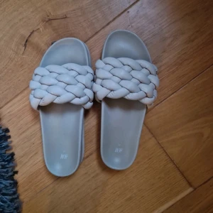 Beige flätade sandaler från H&M - Snygga beige sandaler från H&M i storlek 37. De har en bred, flätad rem över foten och platt sula. Lätta att matcha.