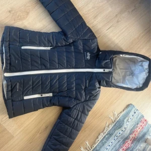Uhip jacka - Jackan har huva, två fickor med dragkedja och diskreta logodetaljer på bröstet och ryggen. Perfekt för kyliga dagar och har en clean, sportig look men även för dem varmare dagarna. Den är använd och har fått en liten ”spricka” där fram men inget som syns när den är på. Annars superfint skick. Storlek 160. Priset är inte helt hugget i sten.