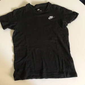 Svart Nike t-shirt i bomull - Svart t-shirt från Nike med klassisk vit logga på bröstet. Enkel och stilren design, rund halsringning och korta ärmar. Tillverkad i mjuk bomull som är skön att ha på sig hela dagen.