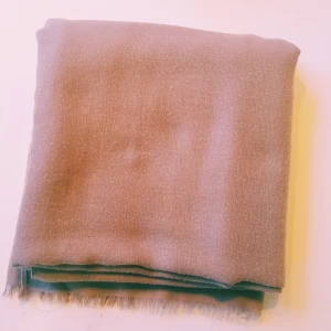 Beige sjal i bomull med fransar - Enkel och stilren beige halsduk i mjuk bomull. Sval och lätt, perfekt att slänga över axlarna. Raka kanter med små fransar i ändarna. Passar till det mesta och är lätt att matcha med olika outfits.  Noppror & ett hål