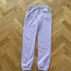 Ljuslila mjukisbyxor från RS Sisters - Supermysiga ljuslila mjukisbyxor från RS Sisters med resår och snörning i midjan samt muddar vid bensluten. Byxorna har två fickor fram och är tillverkade i mjukt material som känns skönt mot huden. Perfekta för chill dagar hemma.