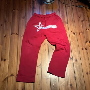 Röda mjukisbyxor från NOFS stl S - Riktigt snygga röda mjukisbyxor från NOFS med vit broderad logga och stjärna framtill. Byxorna har elastisk midja med dragsko och raka ben. Perfekta för chill eller streetwear. Mjukt material som känns skönt mot huden.