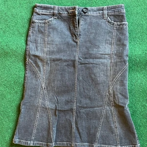 Jeanskjol med snygga sömmar - Jeanskjol i klassisk modell med coola kontrastsömmar och fickor fram. Kjolen har hällor för bälte och stängs med knapp och dragkedja.  Knälång och stretchig. 
