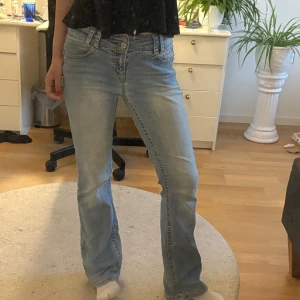  ljusblå bootcut jeans - Lågmidjade bootcut jeans med snygga bakfickorna. De är i bra skick men har lite slitningar längst ner samt några stenar som saknas på bakfickorna men inget man tänker på💕 De störningen storlek men passar mig som brukar ha s. Är 163 cm och passar perfekt i längden!! Tryck gjärna köp nu