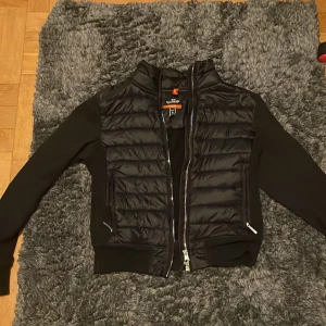 Svart jacka från Parajumpers  - Snygg svart jacka från Parajumpers med quiltad design och dragkedja framtill. Jackan har långa ärmar och är tillverkad i fleece och syntetmaterial. Perfekt för kyligare dagar. junior storlek se bild. Skriv vid funderingar😃