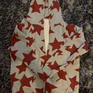Vintage Bape hoodie - Säljer en vintage grå hoodie från Bape med stora röda stjärnor över hela tröjan. Tröjan har huva, dragkedja framtill och långa ärmar. Perfekt för dig som gillar statement-plagg och vill sticka ut lite extra. Topp skick utan några defekter.